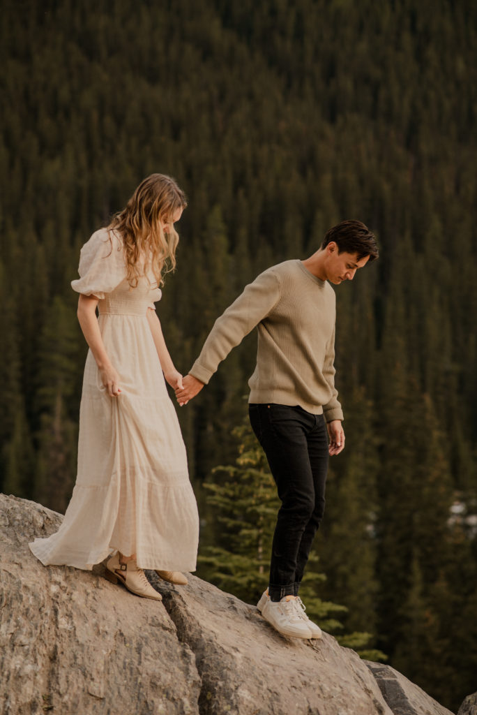 couple walking on rocks during engagement session at moraine lake