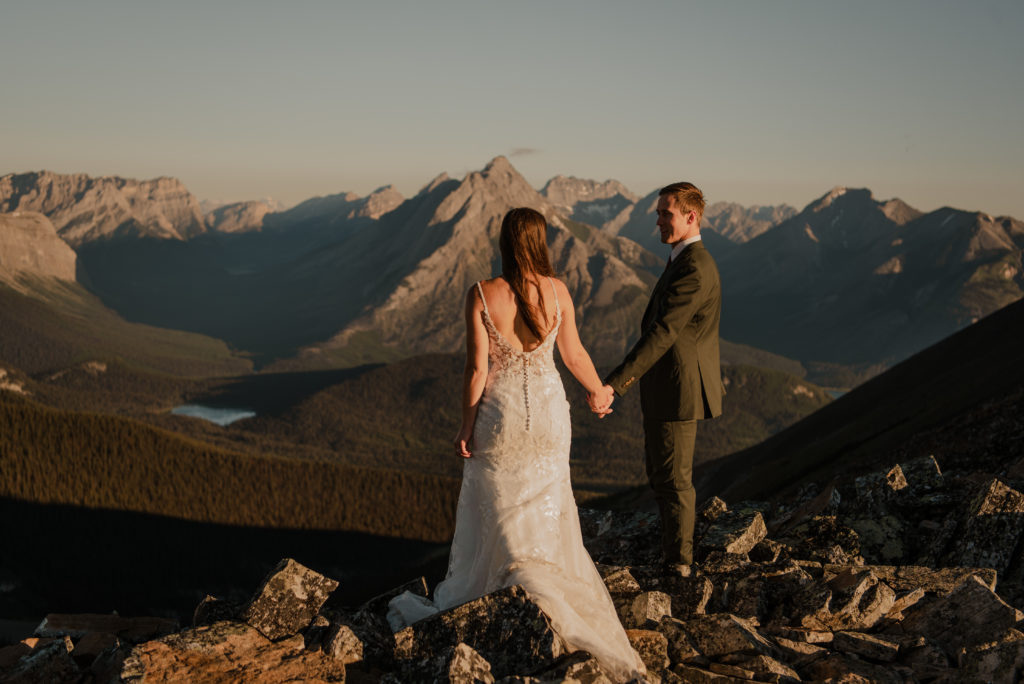 epic views behind the couple during a sunrise hiking elopement in kananaskis