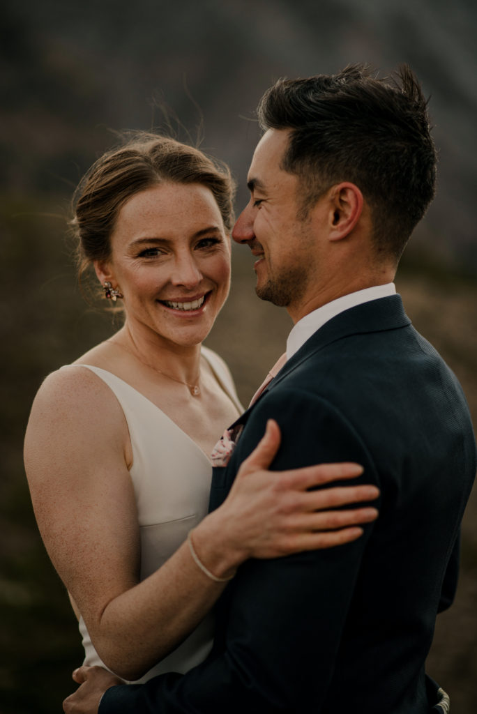 Wedding couple with big smiles closeup on top of a mountain in Kananaskis