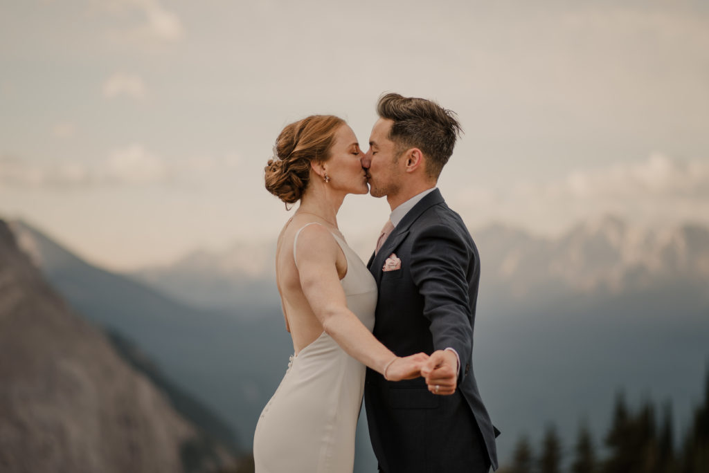 Wedding couple kissing after getting married on top of a mountain in Alberta